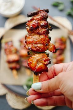 a person is holding up a skewer of food