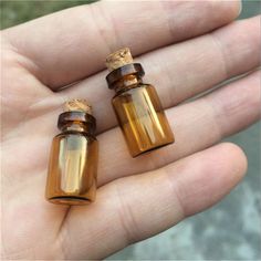 two small glass bottles sitting on top of a person's hand