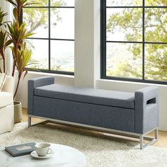 a blue bench sitting in front of a window next to a coffee table and chair