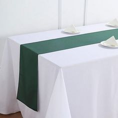 the table is set with white plates and green napkins on it's edge