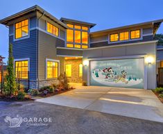 a large house with two garages in front of it at night and lit up windows