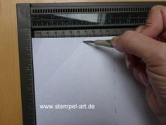 a person holding a pen and writing on a piece of paper with a ruler in front of them