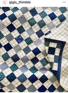 a blue and white quilt is laying on top of a tablecloth that says girs thimble