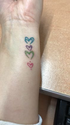 a woman's arm with three hearts tattooed on the left side of her wrist