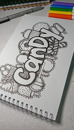 a spiral notebook with the word cool written in black and white on it next to colored pencils