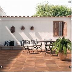 an outdoor patio with potted plants and pots on the side of the house,