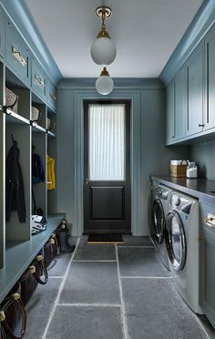 a washer and dryer in a laundry room with blue walls, grey flooring and cabinets