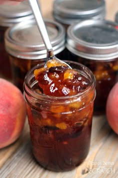 a jar filled with jelly sitting on top of a table next to some peaches