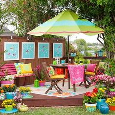 an outdoor patio with colorful furniture and flowers on the ground next to a wooden fence