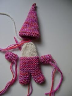 a pink and white knitted doll laying on top of a table next to a string