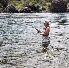 a woman standing in the water while fishing