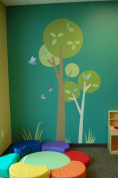 the children's room is decorated with colorful furniture and wall decals, as well as a tree painted on the wall