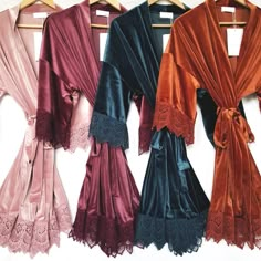 four robes hanging up on a rack with lace trims and bows at the waist