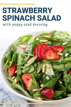 a salad with spinach, strawberries and almonds in a white bowl on a blue towel