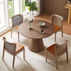 a round table with chairs around it in a room next to a window and potted plant