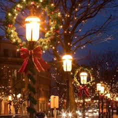 christmas lights and wreaths adorn the street at night