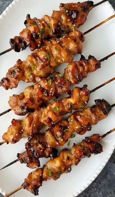 several skewers of chicken on a white plate