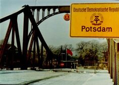 a yellow sign that is hanging from the side of a metal bridge over snow covered ground