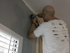 a man is working on the ceiling in his home with an electric drill and screwdriver