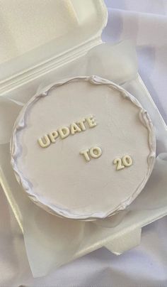 a white cake with the words update to 20 in gold lettering on it sitting in a box