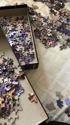 a box filled with puzzle pieces on top of a bed