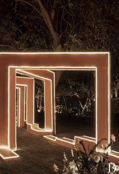 an archway lit up at night with lights on the sides and trees in the background