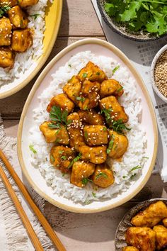 two plates filled with chicken and rice next to chopsticks