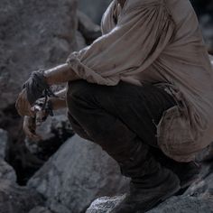 a man sitting on top of a rock next to a pile of dirt and rocks