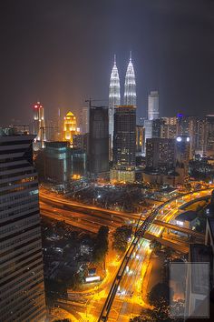 the city skyline is lit up at night with lights and buildings in the foreground