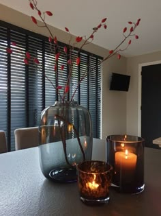 two candles sitting on top of a table next to a vase with flowers in it