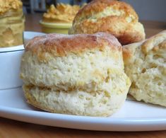 three biscuits on a white plate next to cupcakes