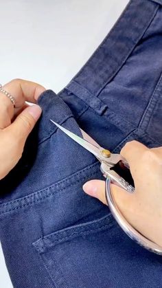 someone is cutting through the back pocket of their jean pants with a pair of scissors