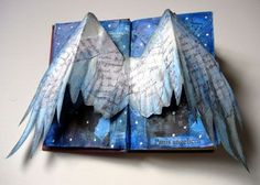 an open book with paper wings on it