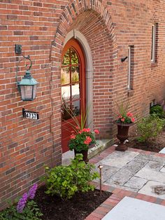 a brick building with potted plants in front of the door and on the side