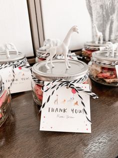 a table topped with glass jars filled with food and thank you cards on top of it