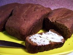 a loaf of brown bread sitting on top of a yellow plate next to a knife