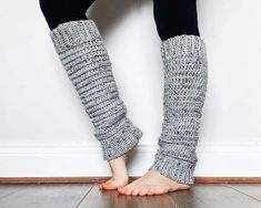 the legs and feet of a woman wearing knitted leg warmers, standing in front of a white wall