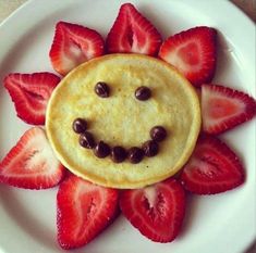 a smiley face made out of strawberries on a plate