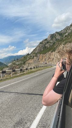 a woman sitting in the passenger seat of a car while talking on her cell phone