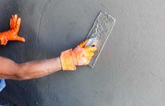 a person wearing orange gloves is painting a wall