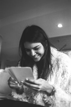 black and white photograph of woman in fur coat looking at tablet