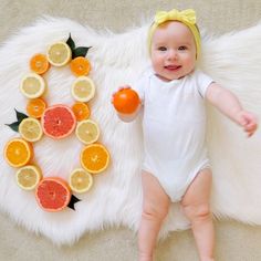 a baby is laying on the floor next to sliced oranges and an orange slice