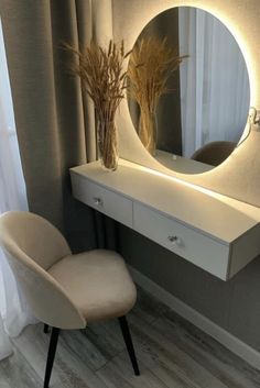 a white chair sitting in front of a mirror on top of a dresser next to a tall plant