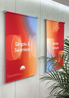 two red banners hanging on the wall next to a potted palm tree in an office building