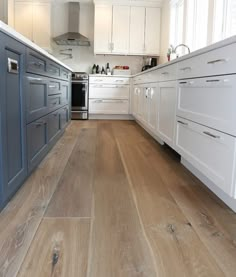 a kitchen with white cabinets and wood floors is shown in this image from the front view