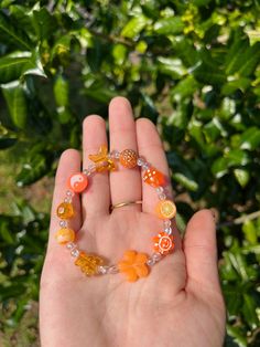 a person holding their hand in front of some leaves and oranges on the palm