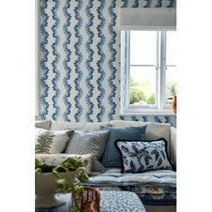 a living room with blue and white wallpaper on the walls next to a window