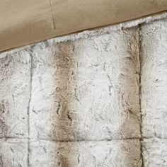 a close up of a bed with white and brown fur on it's sides