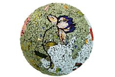 a mosaic ball with flowers and leaves painted on it's side, sitting in front of a white background