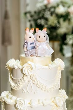 a wedding cake with two rabbits on top